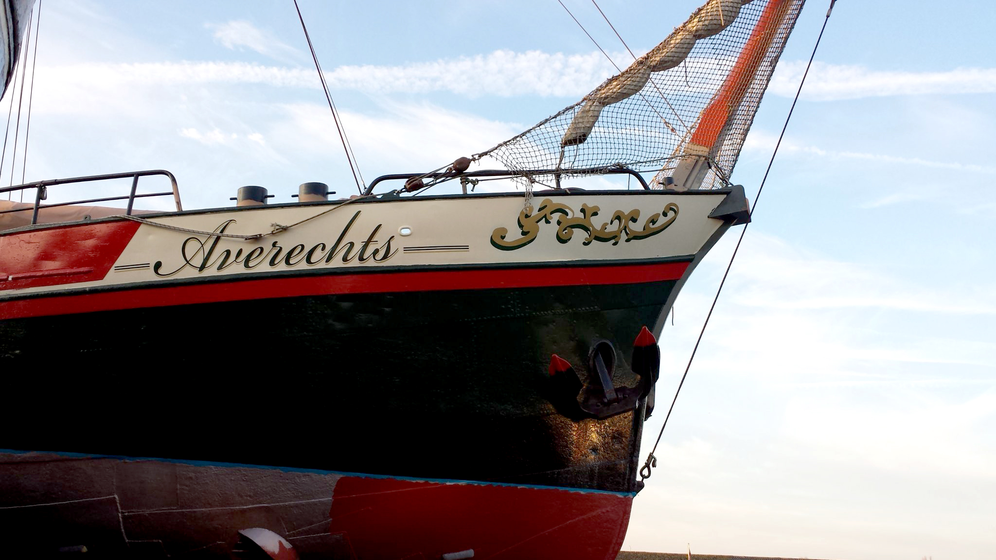 Boeg van een historisch schip met de scheefletter Averechts en gouden versiering, ook is het anker zichtbaar