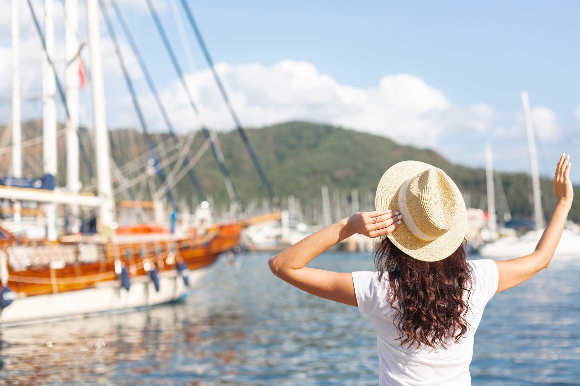 Femme dans le port, de dos, faisant signe au bateau